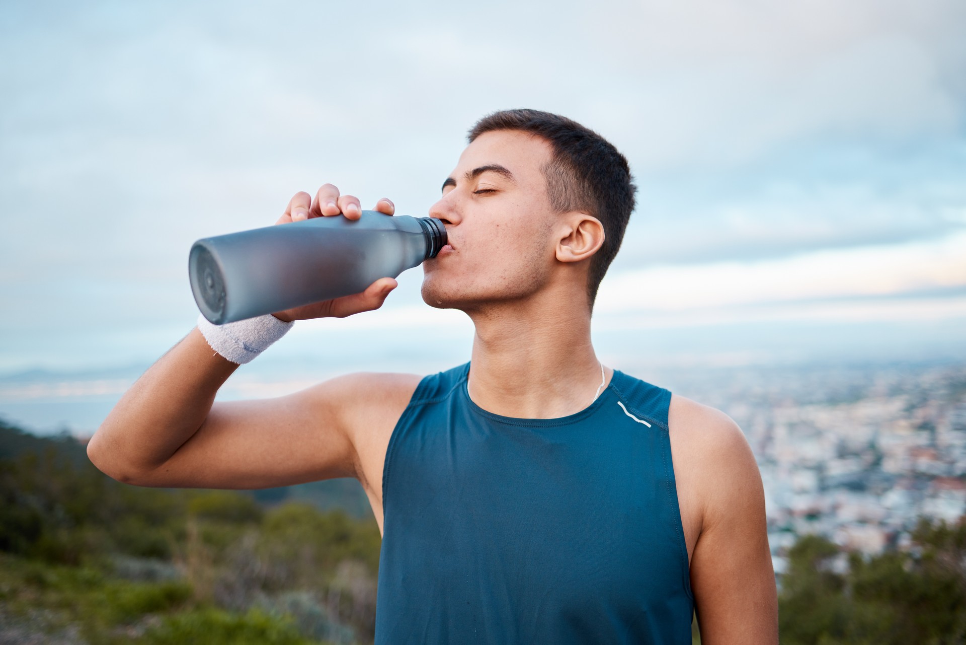 Uomo, fitness e acqua potabile in natura, allenamento o esercizio all'aperto durante la pausa, il riposo o il recupero. Persona maschile assetata, bevanda sportiva o minerale per la sostenibilità dopo la corsa, il cardio o l'allenamento